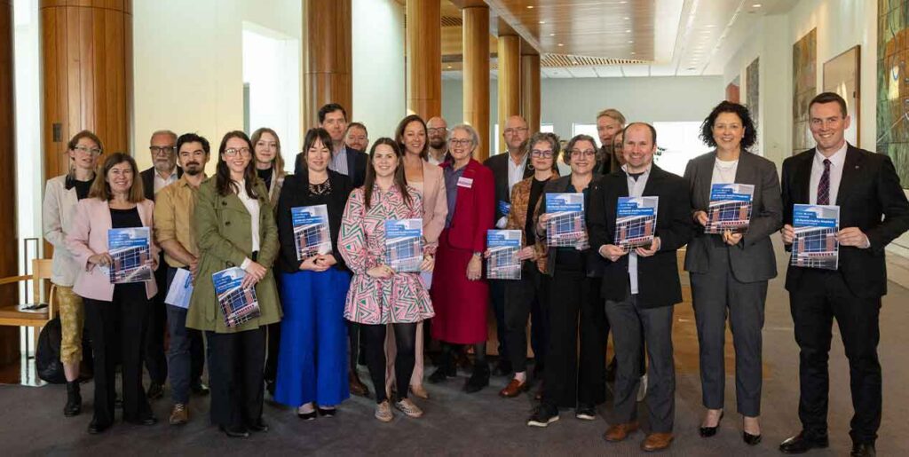 Group of smiling people holding up copies of the report